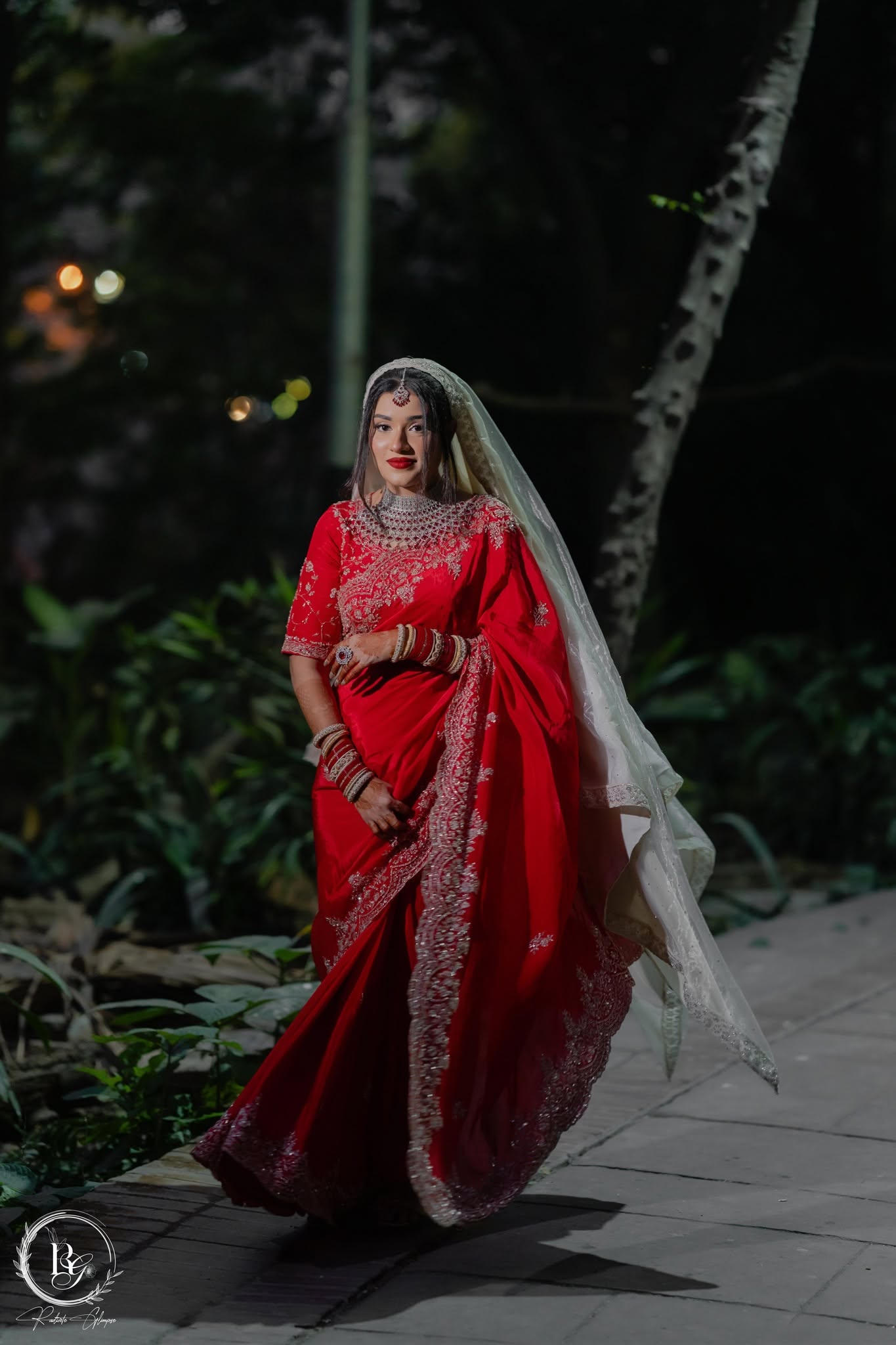 Bride in red saree at night garden